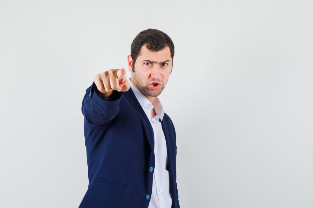 takım elbiseli bir adam kameraya tehdit ile işaret ediyor